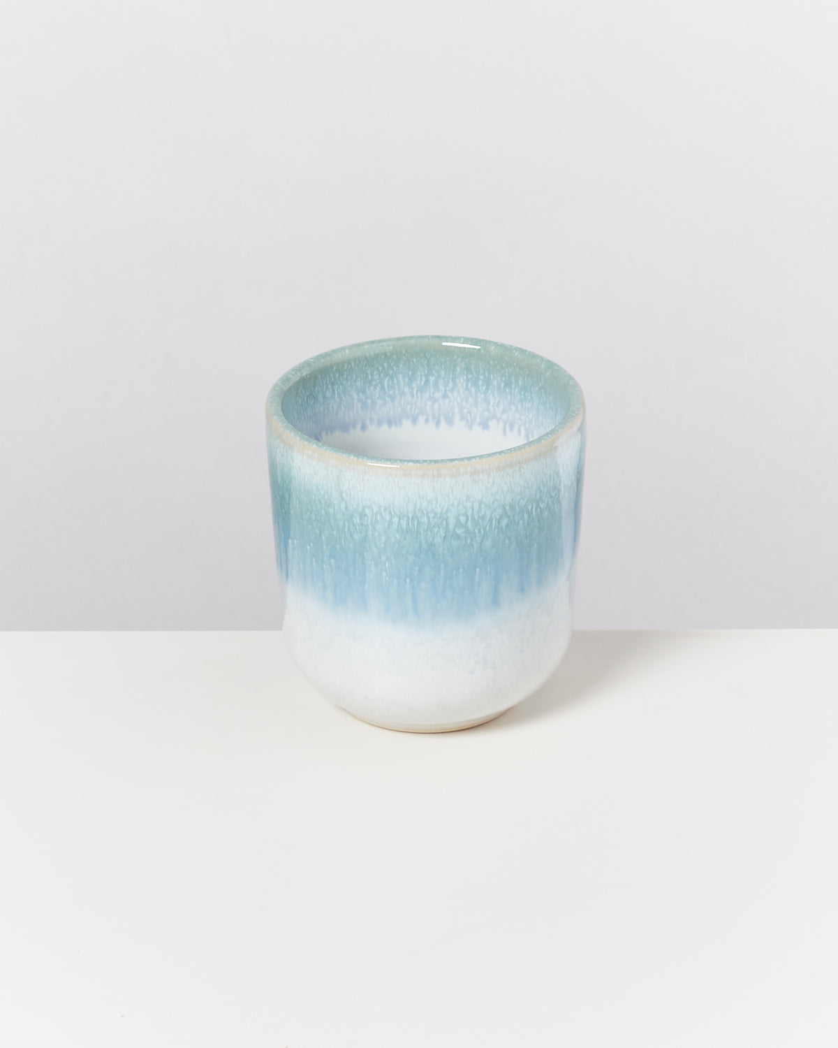 Keramikbecher mit blau-weißen Farbverläufen auf einem weißen Hintergrund.