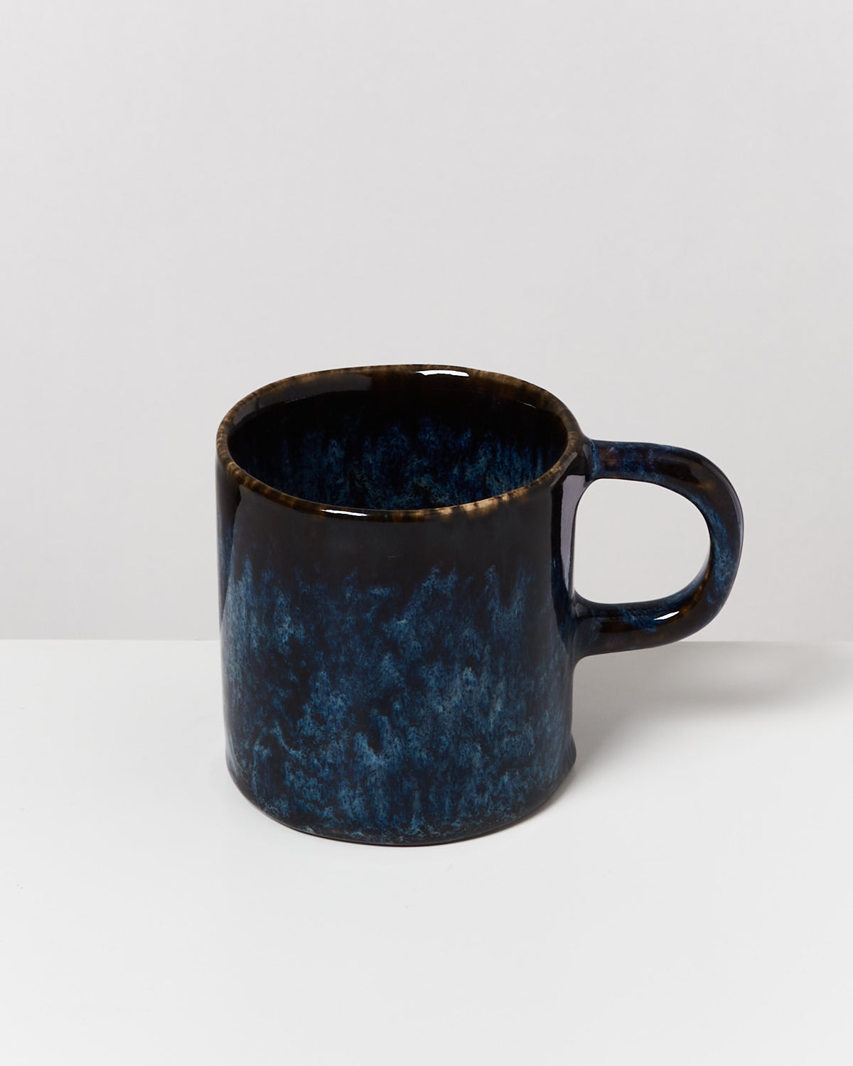 Dunkelblaue, strukturierte Keramiktasse auf weißem Hintergrund.