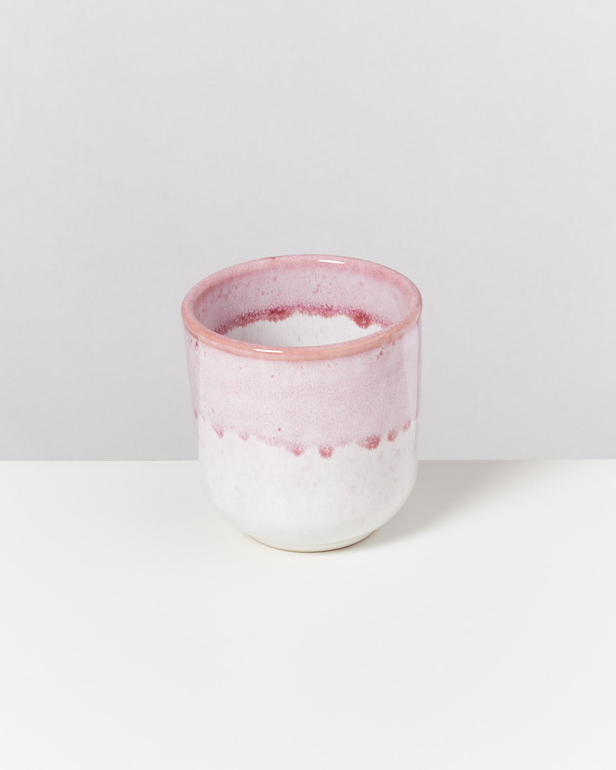 Rosa-weißer Keramikbecher mit glasiertem Finish auf weißem Hintergrund.