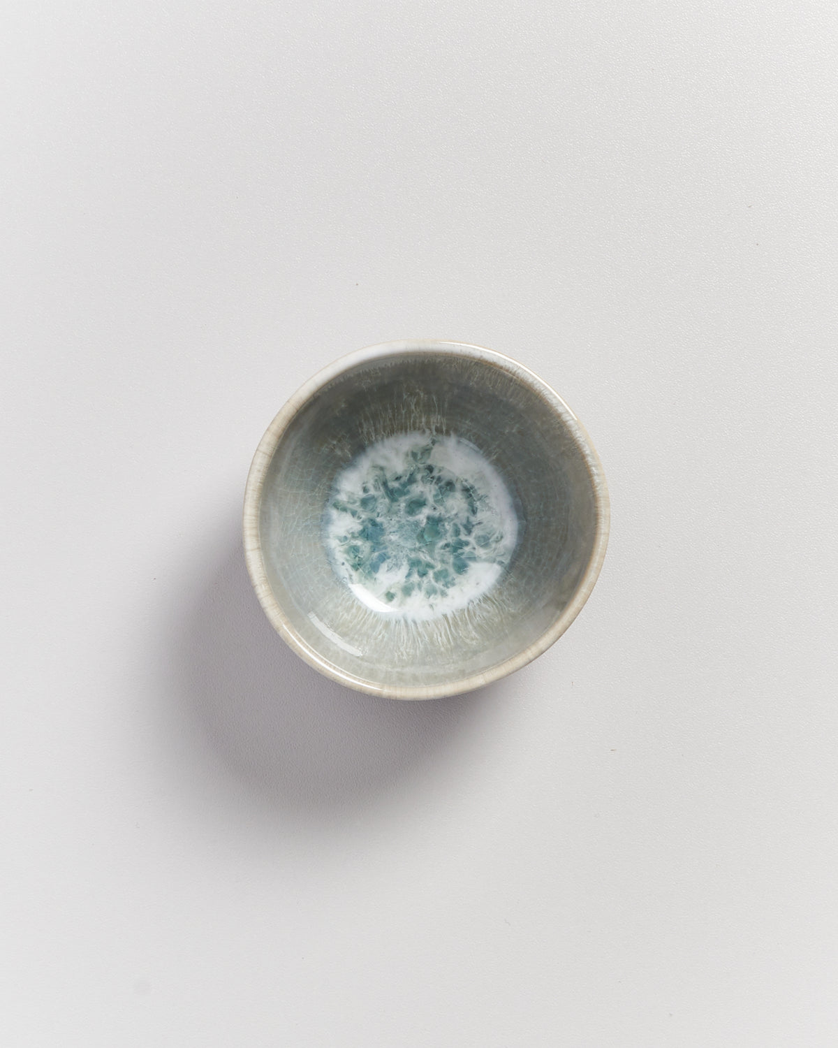 Kleine graue Keramikschale mit blau-weißem Muster auf hellem Hintergrund.