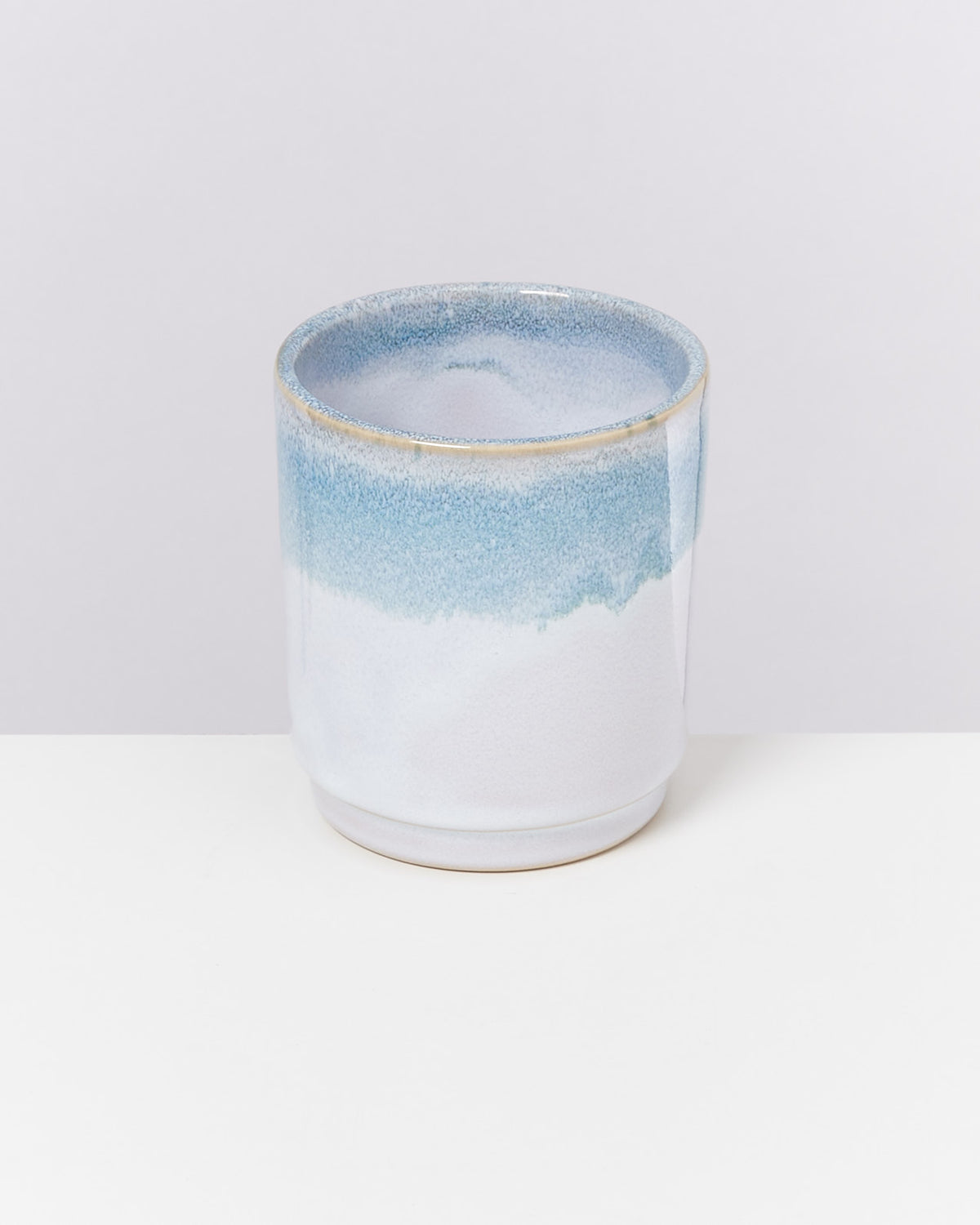 Keramiktasse mit blau-weißem Farbverlauf auf einem weißen Hintergrund.