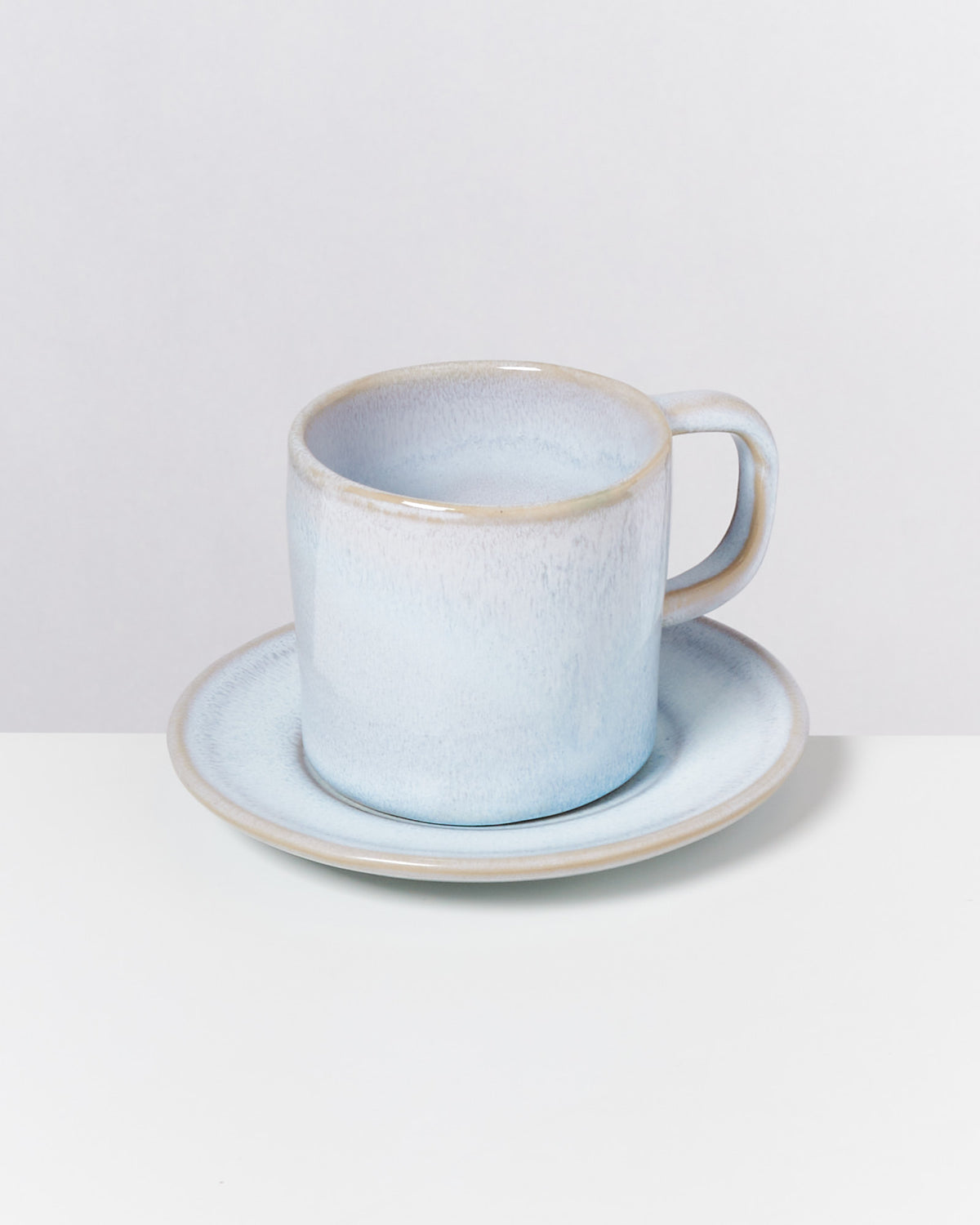 Blaue Keramiktasse mit Untertasse auf einem weißen Hintergrund.