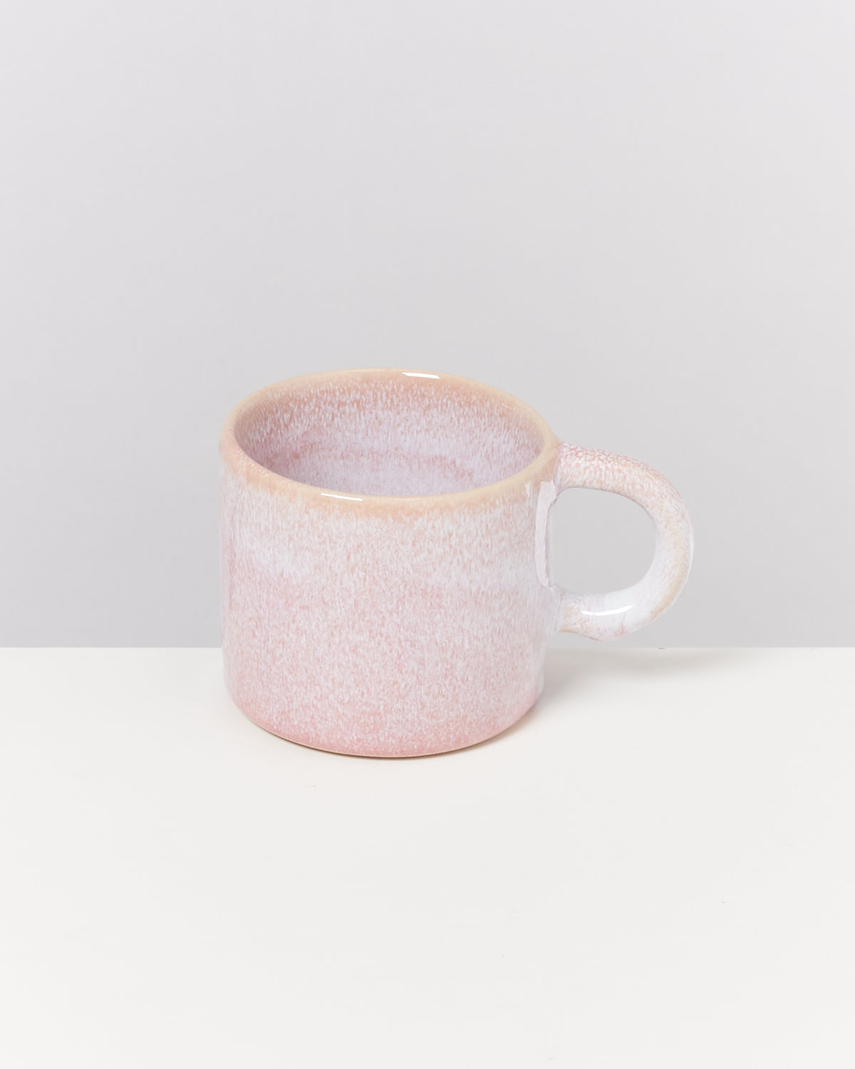 Rosa Keramiktasse mit Henkel auf weißem Hintergrund.