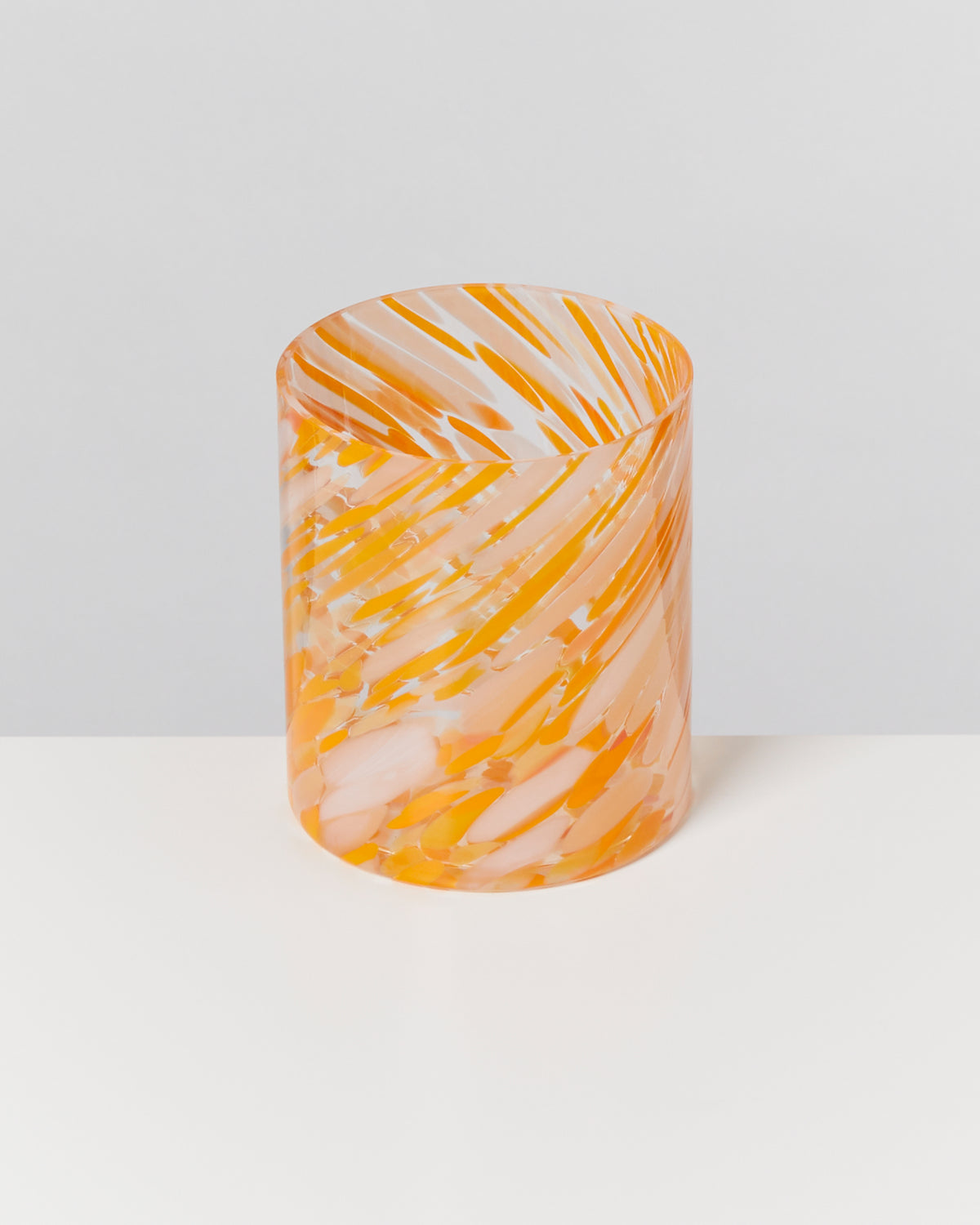 Transparenter Zylinder mit orange-weißen Wirbelmustern auf einem weißen Hintergrund.