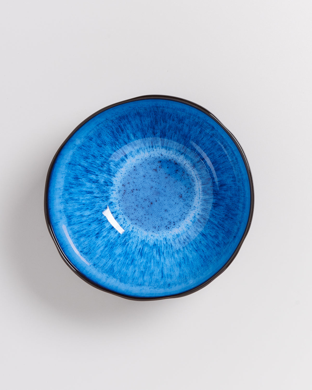Blaue Schale mit dunklem Rand und gesprenkeltem Muster auf weißem Hintergrund.