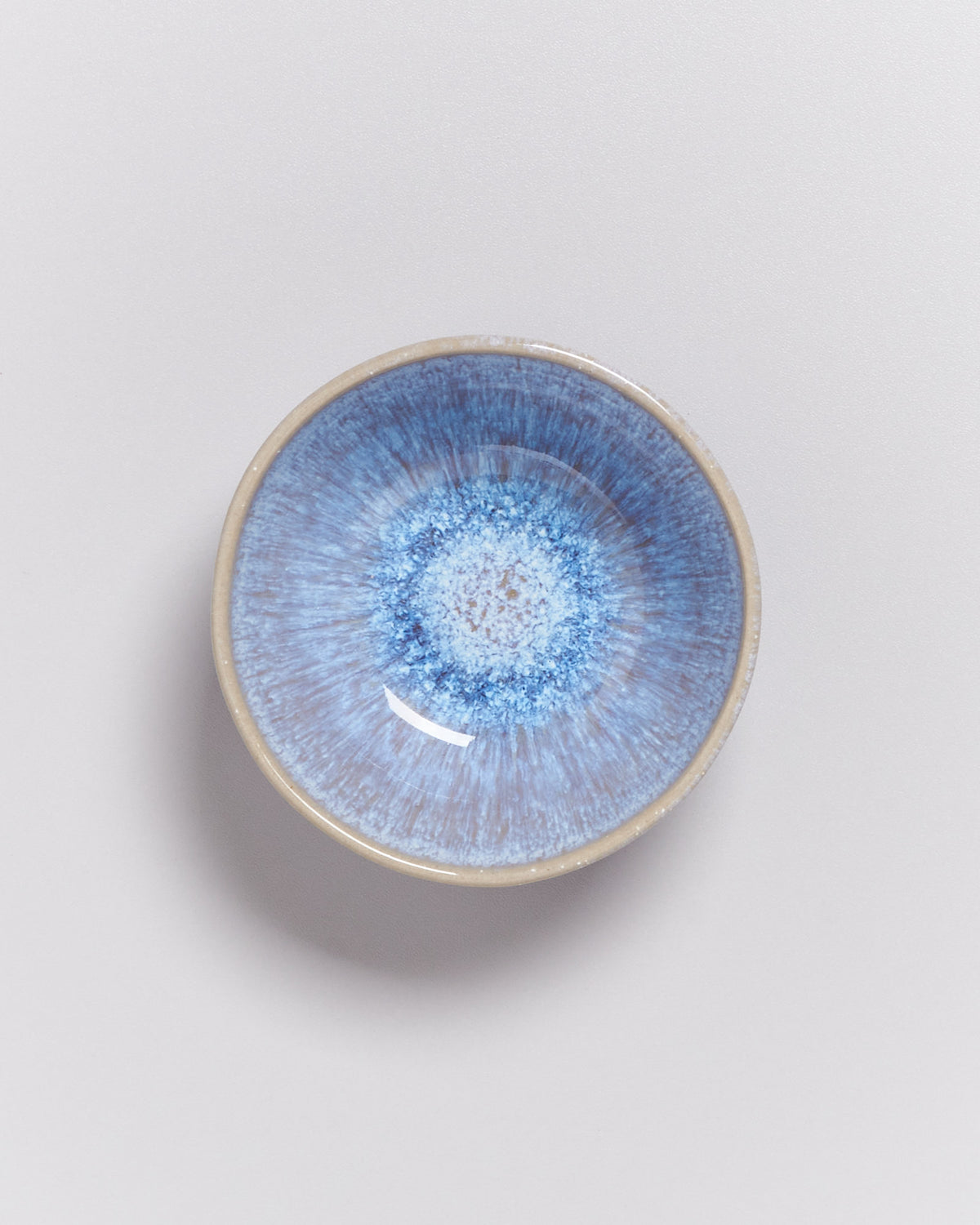 Kleine, runde Keramikschale mit blauem, gesprenkeltem Muster auf hellem Hintergrund.