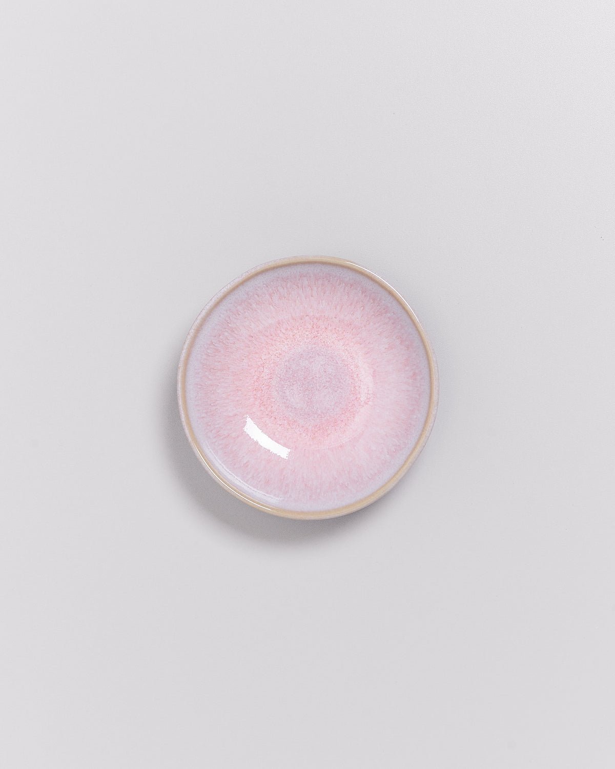 Keramikteller mit rosa Farbverlauf auf grauem Hintergrund.