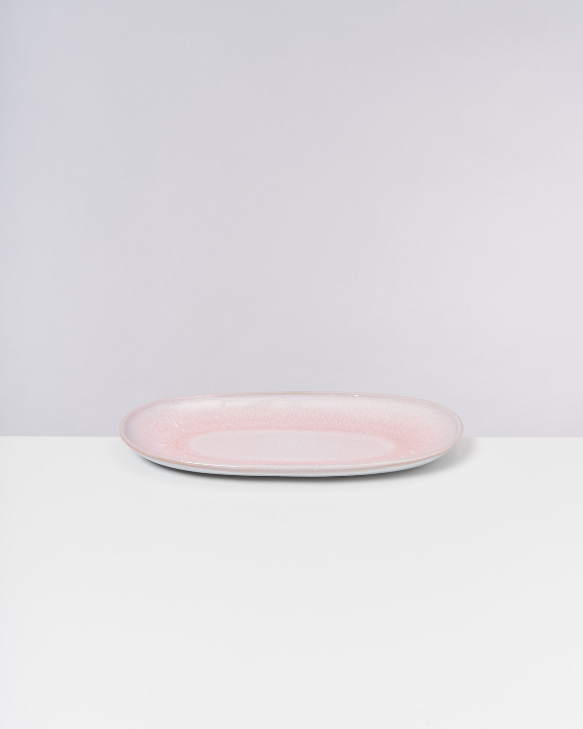 Ovaler, rosa Teller auf weißem Hintergrund.