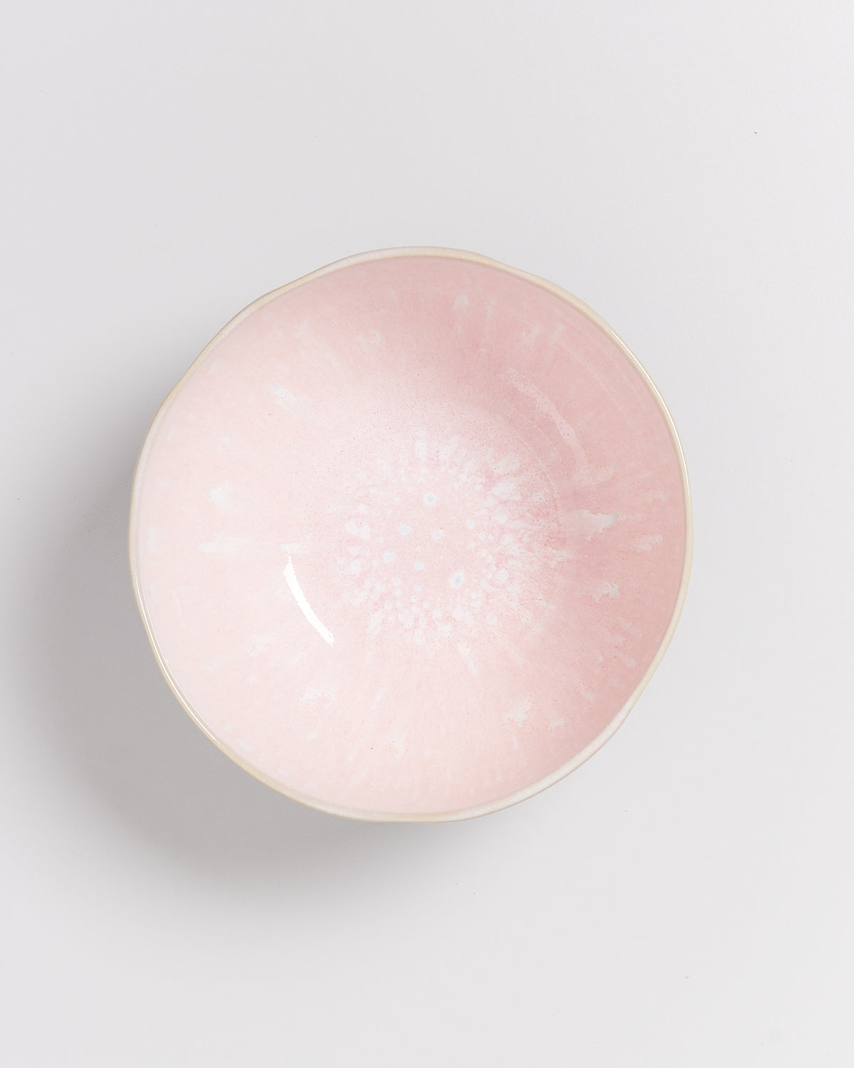 Eine rosa Schale mit pastellfarbenem Muster auf weißem Hintergrund, von oben gesehen.