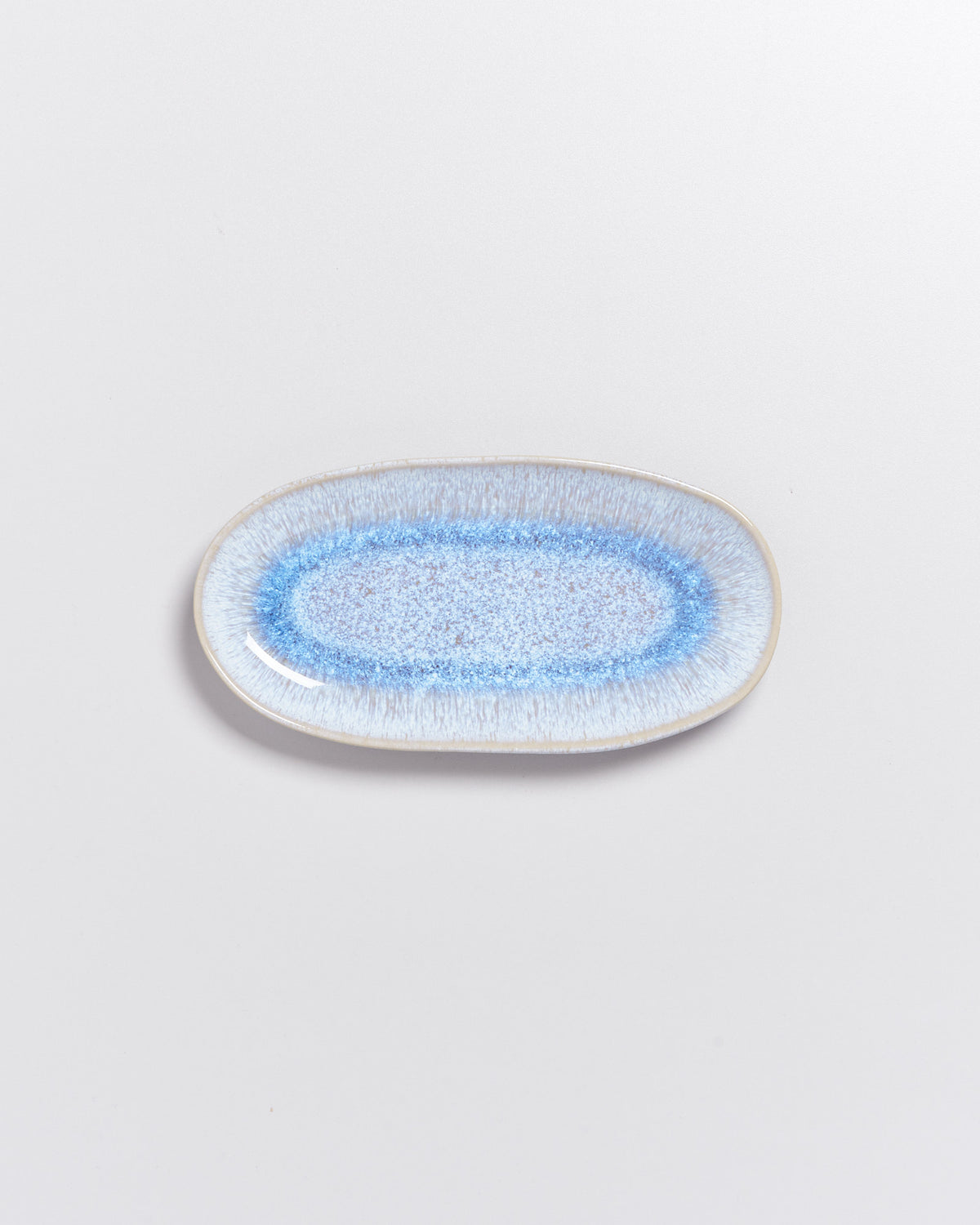 Ovaler Keramikteller mit blauem, gesprenkeltem Muster auf weißem Hintergrund.