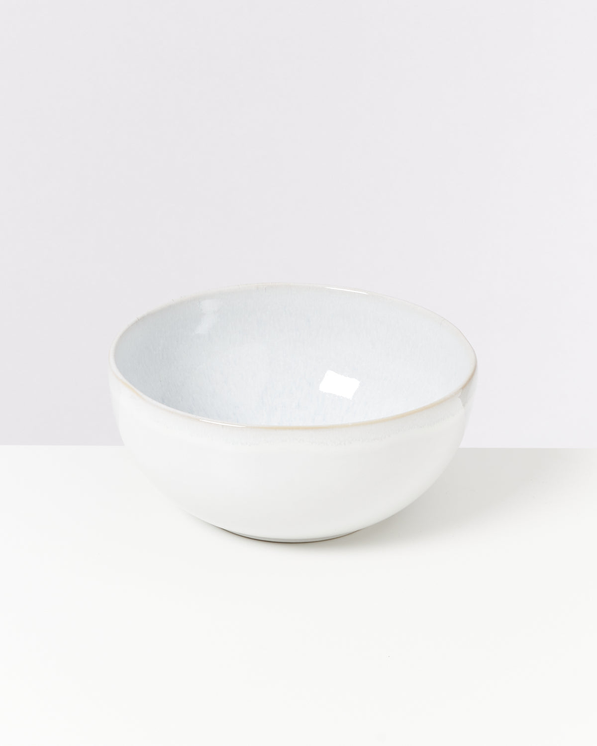 Weiße Keramikschüssel mit leicht glänzender Oberfläche auf einem weißen Hintergrund.