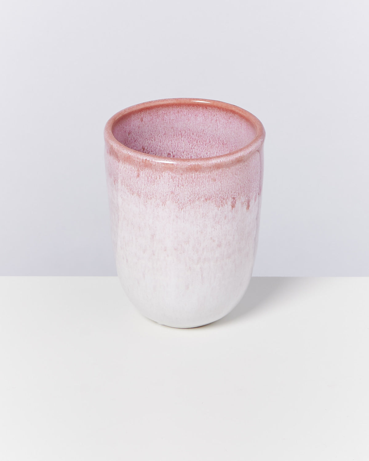 Keramikbecher mit rosa und weißem Farbverlauf auf weißem Hintergrund.