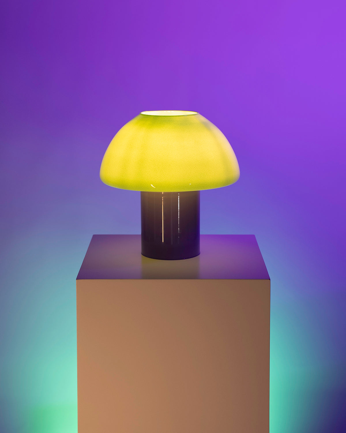 Gelbe, pilzförmige Lampe auf einem Podest, vor einem violetten Hintergrund beleuchtet.